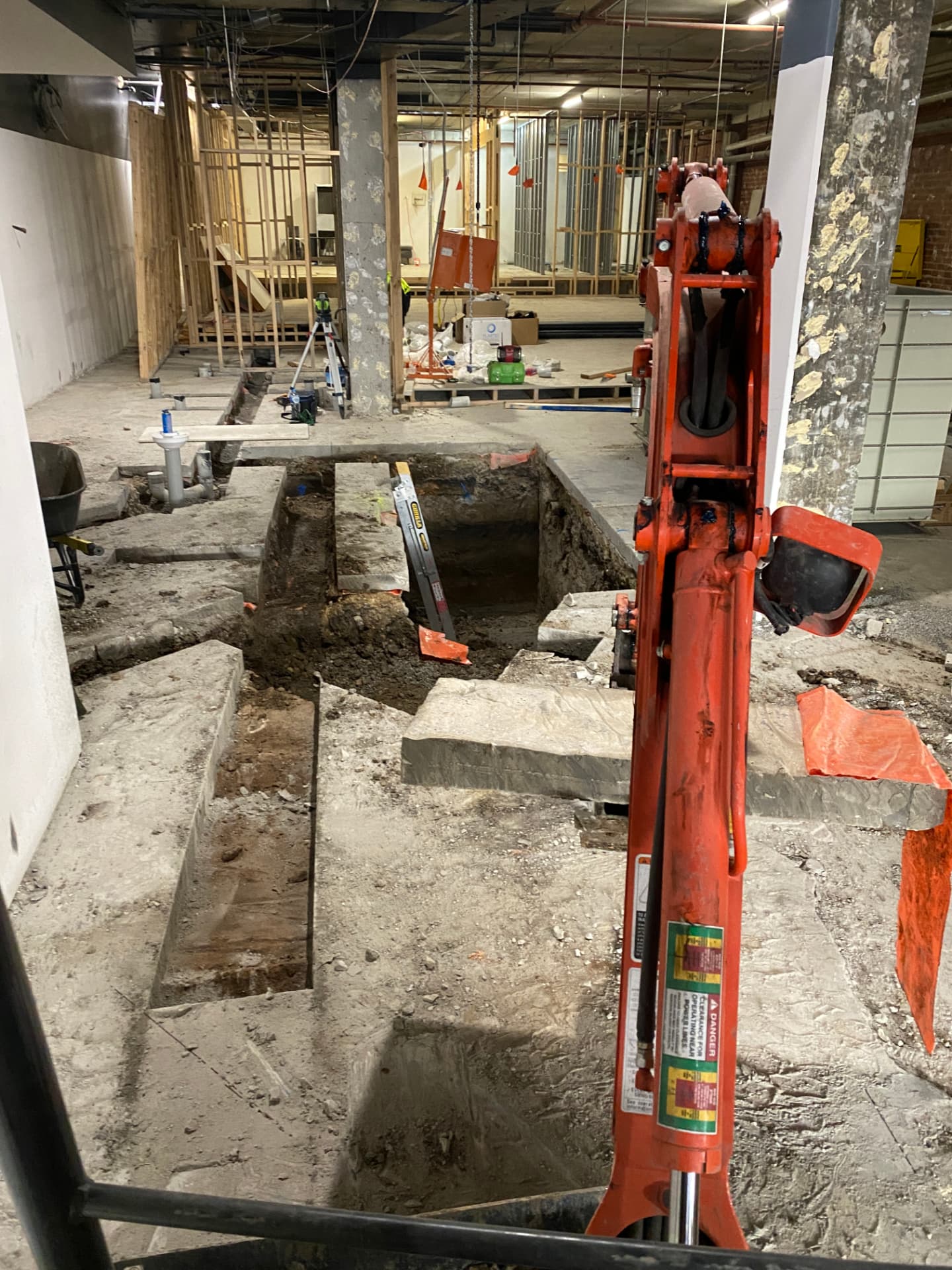 Excavator digging trenches inside a commercial fit-out for a grease trap installation